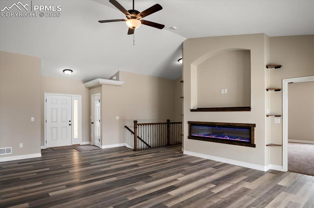 Image 11 of 45: Unfurnished living room featuring a glass covered fireplace, wood finished 