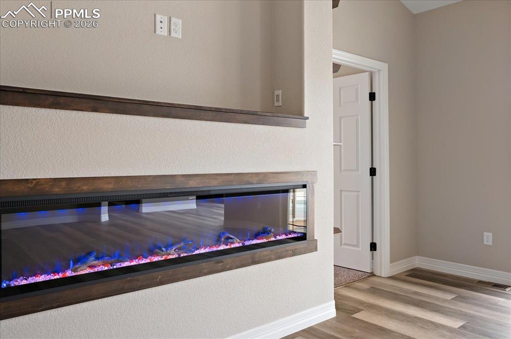 Image 13 of 45: Detailed view of a textured wall, wood finished floors, and a glass covered