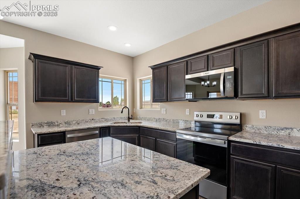 Image 16 of 45: Kitchen featuring appliances with stainless steel finishes, light stone cou