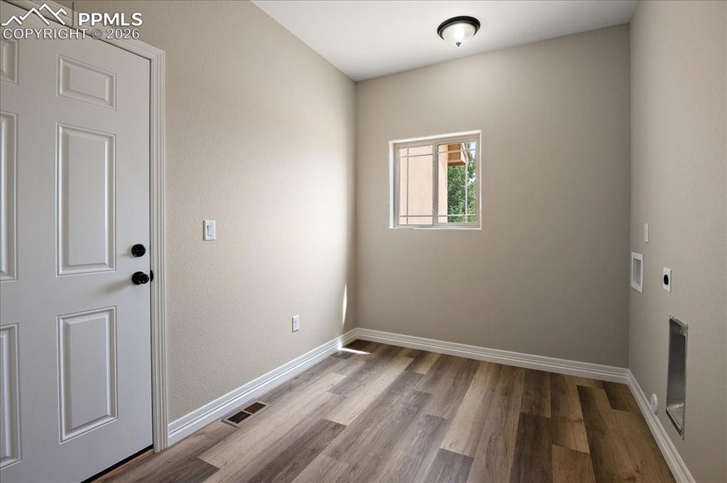 Image 18 of 45: Laundry area featuring electric dryer hookup, light wood finished floors, a
