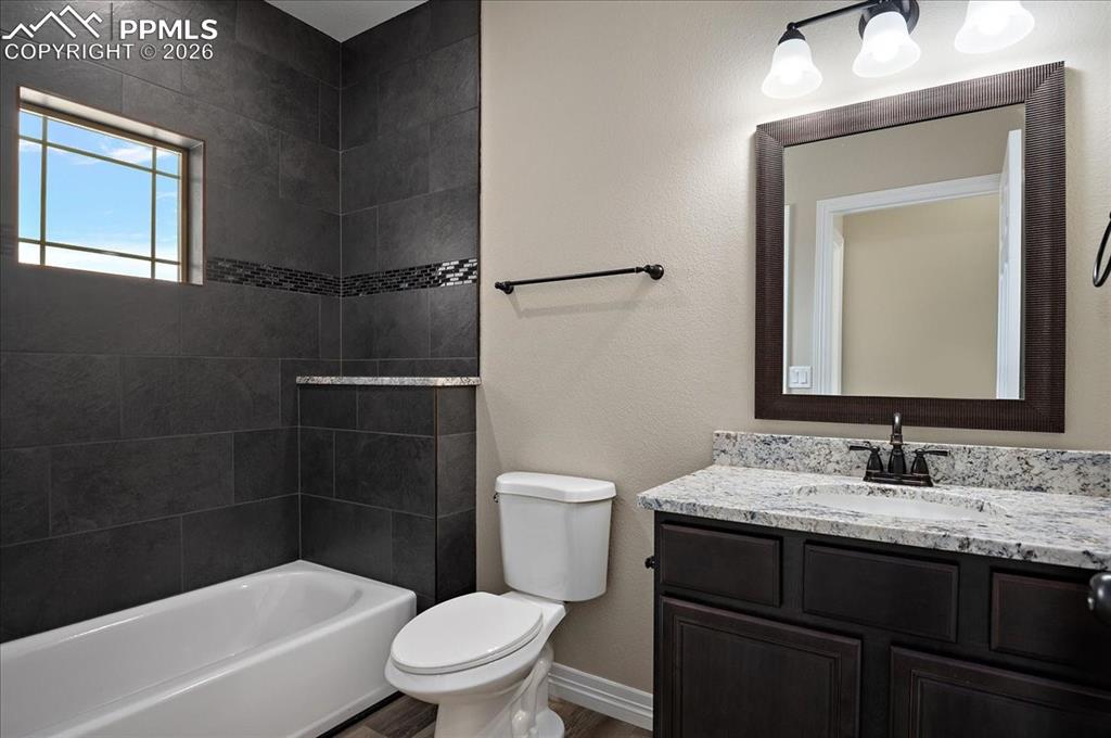 Image 22 of 45: Full bathroom featuring a textured wall, vanity, shower / tub combination, 