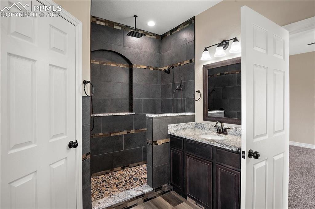 Image 28 of 45: Bathroom featuring tiled shower and vanity