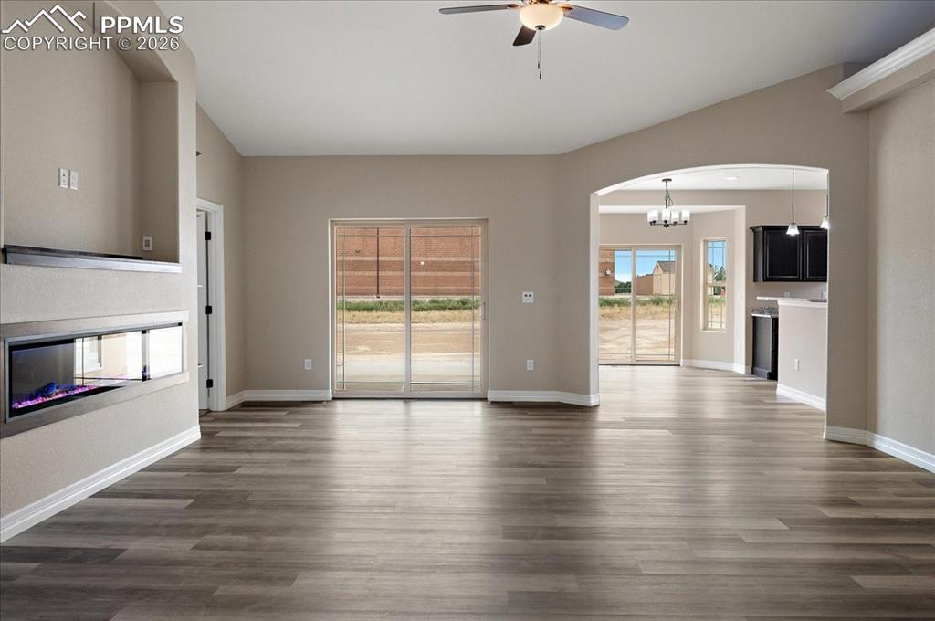 Image 3 of 45: Unfurnished living room with arched walkways, a multi sided fireplace, a ce