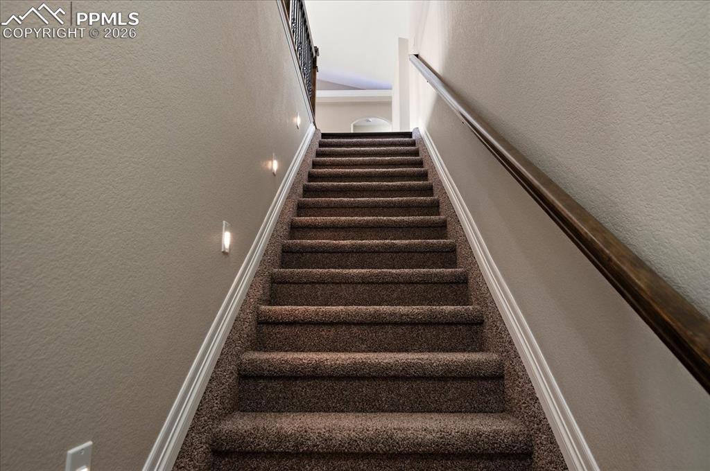 Image 33 of 45: Stairs featuring a textured wall and carpet floors