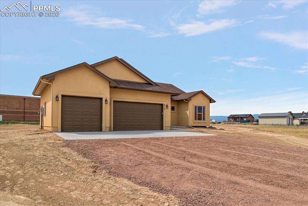 Image 38 of 45: Ranch-style house featuring a garage, stucco siding, and driveway