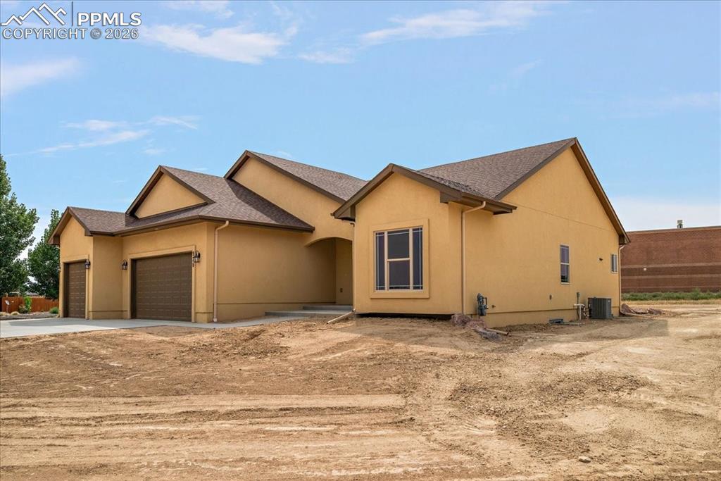 Image 39 of 45: View of front facade featuring a garage, roof with shingles, stucco siding,