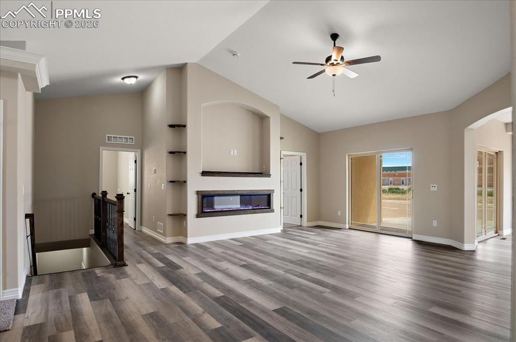 Image 4 of 45: Unfurnished living room featuring a glass covered fireplace, ceiling fan, d