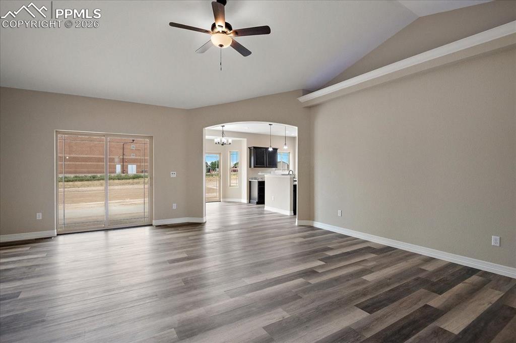 Image 5 of 45: Unfurnished living room with a chandelier, ceiling fan, dark wood-style flo