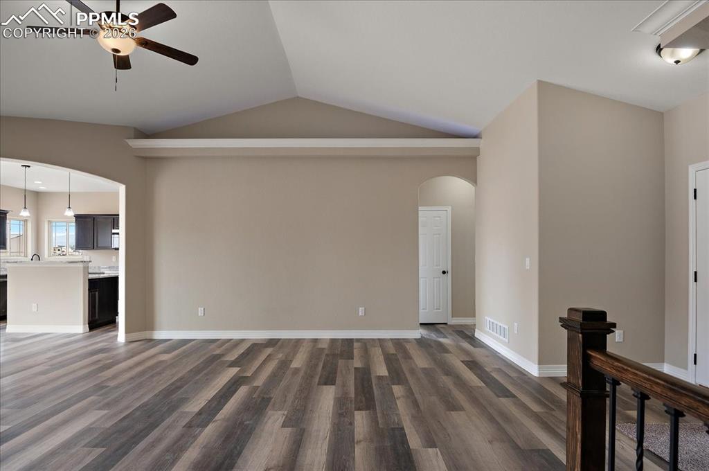 Image 6 of 45: Unfurnished living room featuring arched walkways, dark wood-type flooring,