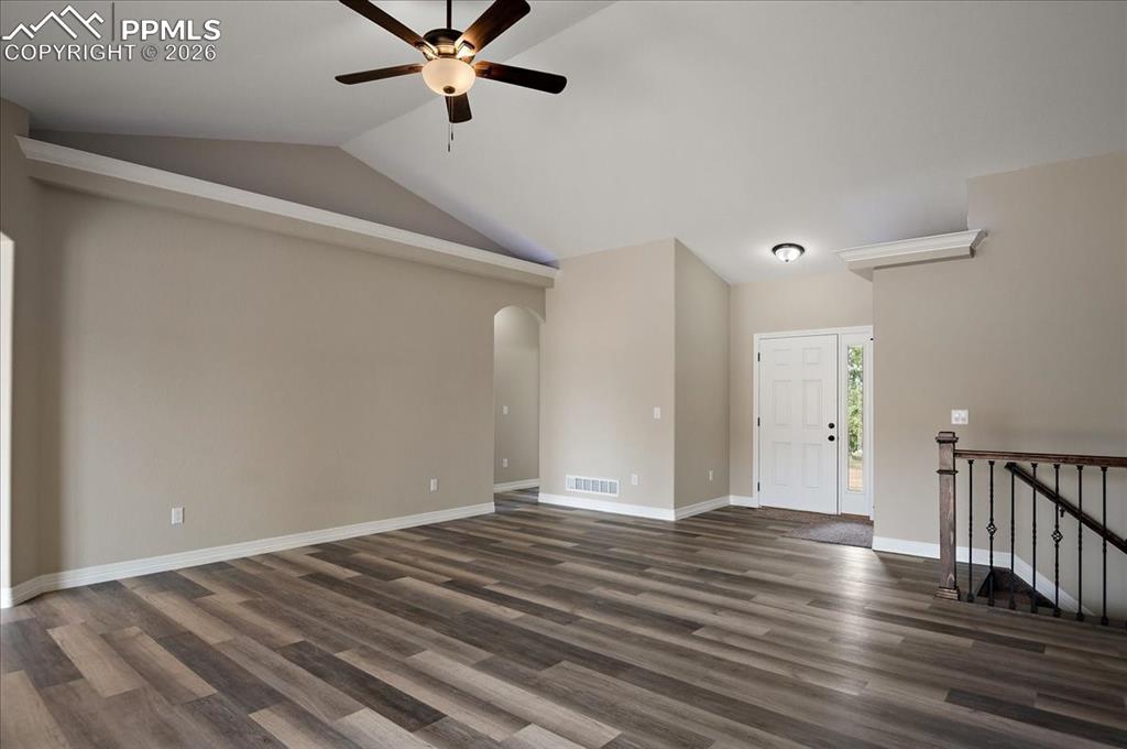 Image 8 of 45: Unfurnished living room with vaulted ceiling, dark wood-type flooring, arch