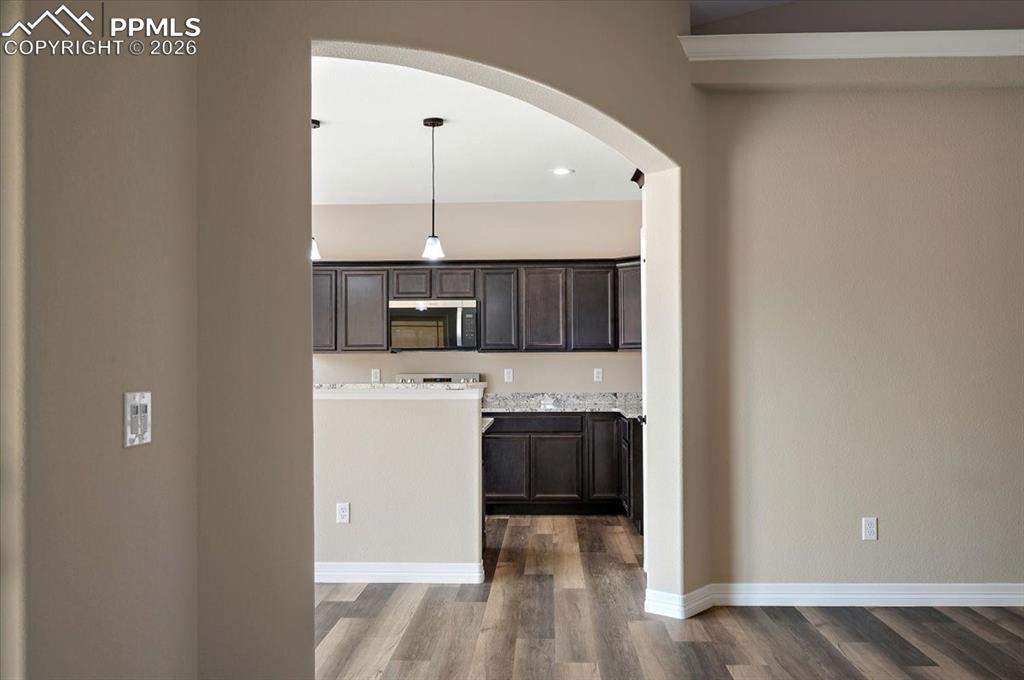 Image 9 of 45: Kitchen with arched walkways, dark wood finished floors, stainless steel mi