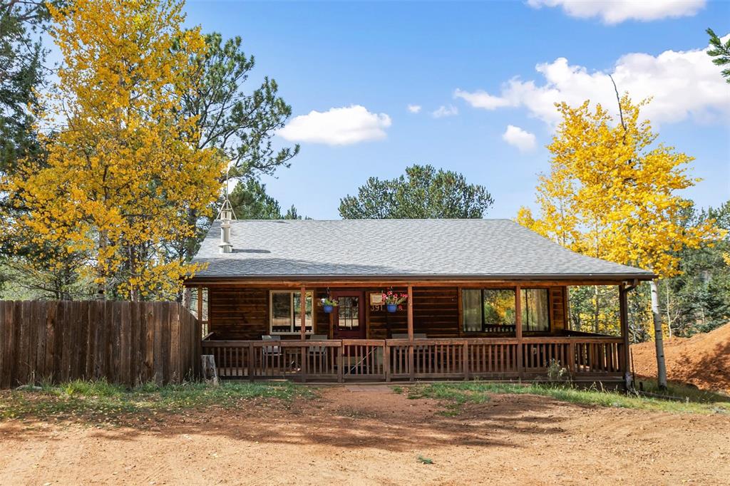 Image 10 of 36: Wood-sided residence featuring a covered front porch with a wooden railing