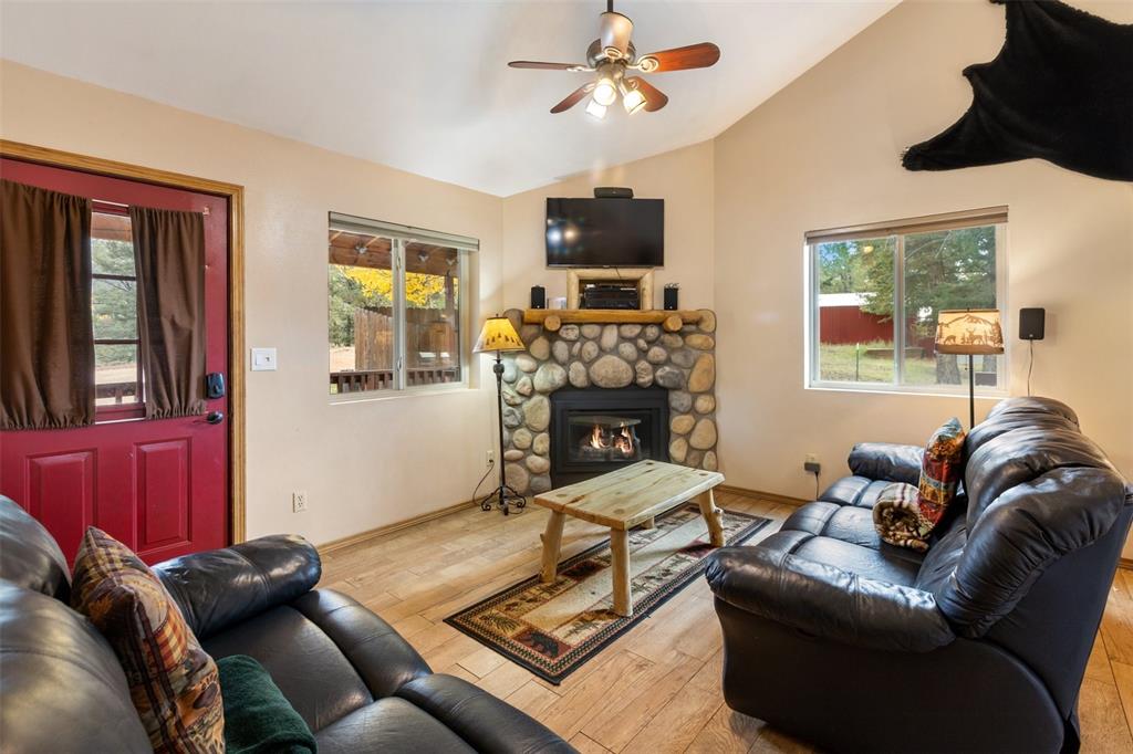 Image 11 of 36: Vaulted ceiling with ceiling fan, stone-faced fireplace with wood mantel, w