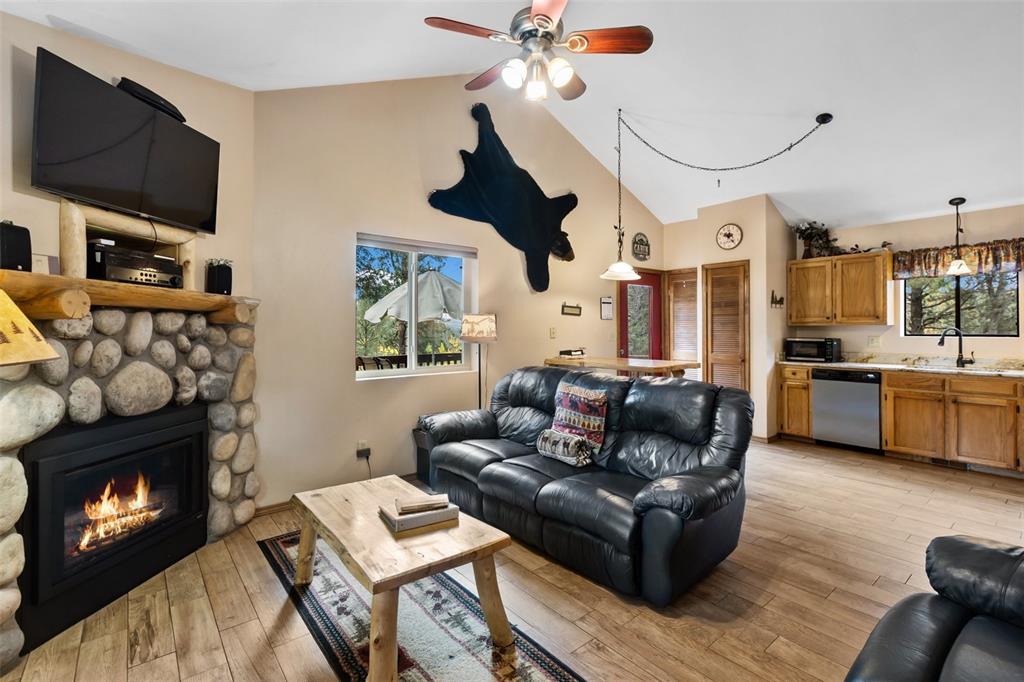 Image 13 of 36: Stone-clad fireplace with wood mantle, wood-finish flooring, vaulted ceilin
