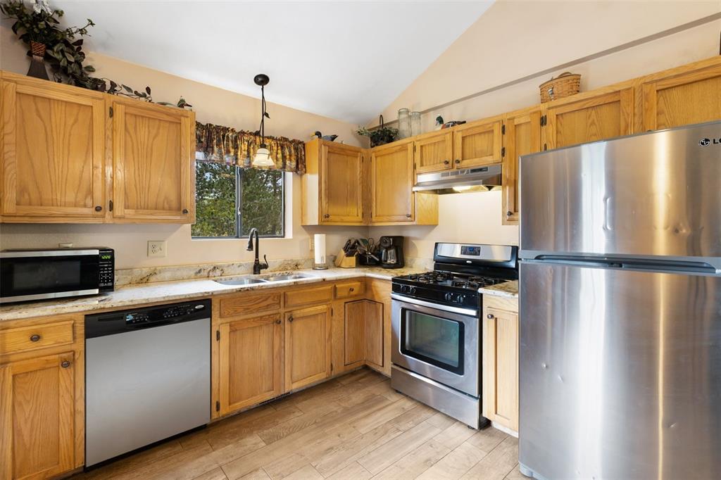 Image 17 of 36: Kitchen featuring wood-finish cabinetry, stainless steel appliances, granit