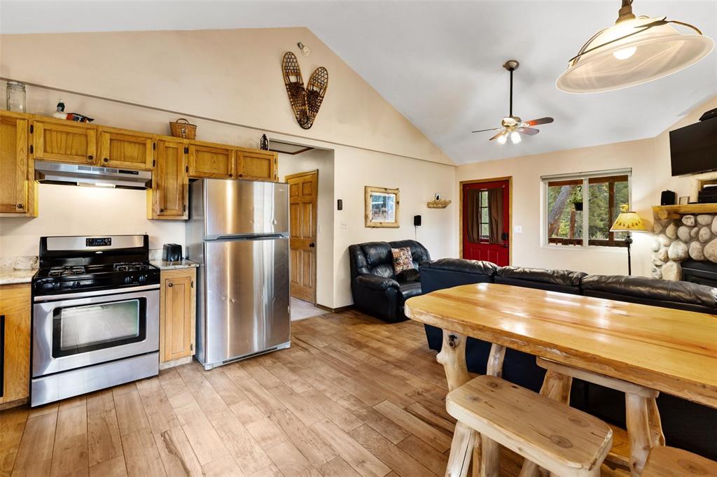 Image 18 of 36: Open-concept living space with vaulted ceilings, wood-finish flooring, and 