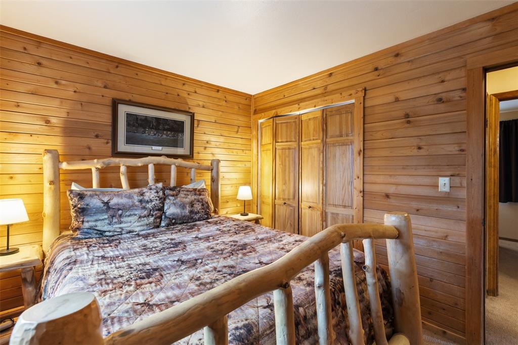Image 23 of 36: Wood-paneled walls with natural grain, wood-finish bi-fold closet doors, an