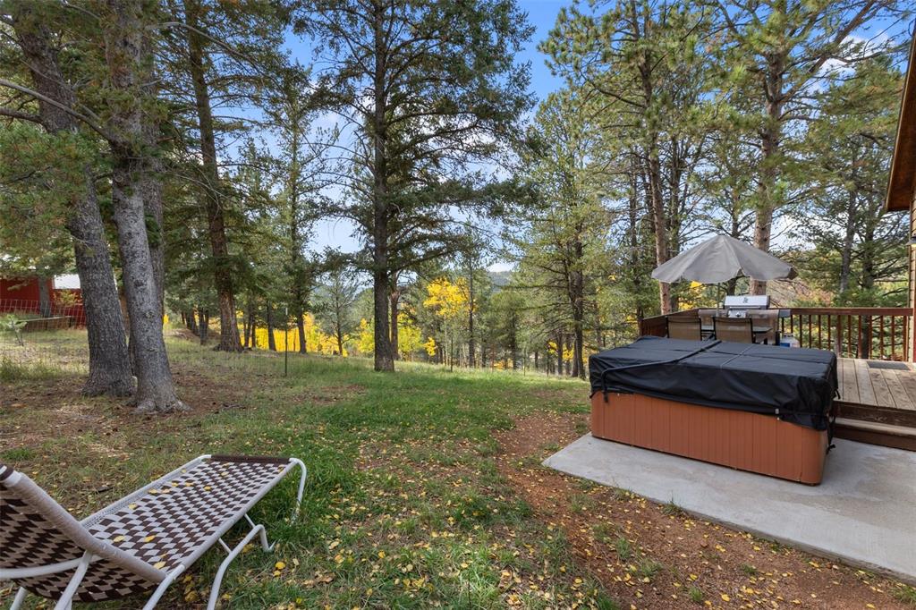 Image 30 of 36: Expansive outdoor space featuring a hot tub, wood-finish decking, and matur