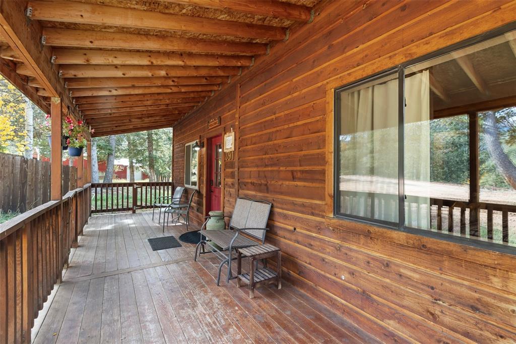 Image 33 of 36: Expansive wood-plank porch with exposed beam ceiling, wood railing, and nat