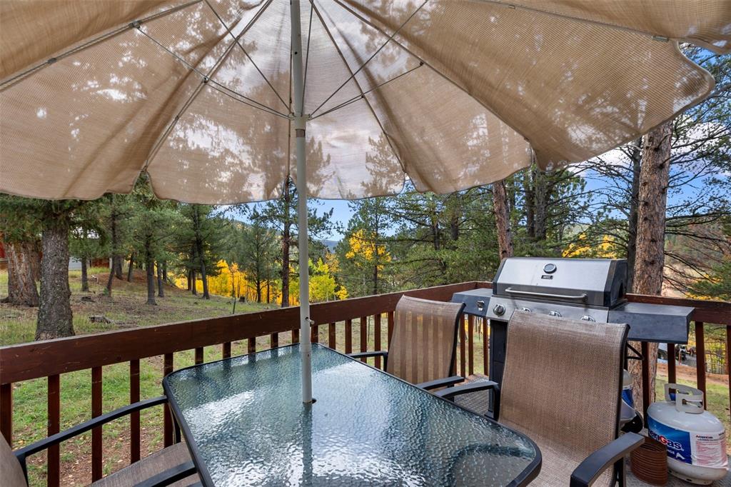 Image 6 of 36: Outdoor deck with wood railings, integrated gas grill, and glass-top table