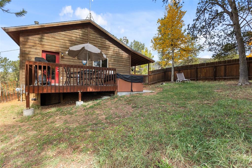 Image 7 of 36: Wood-sided exterior featuring an elevated deck with a hot tub and a private