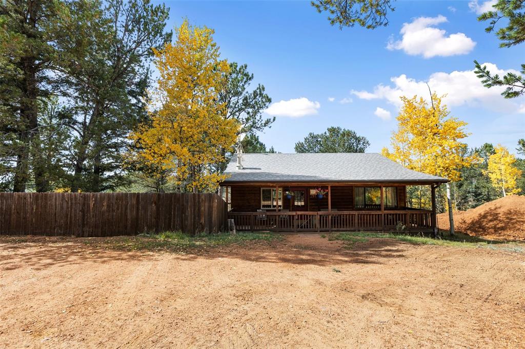 Image 9 of 36: Log cabin exterior with a covered front porch, an asphalt shingle roof, and