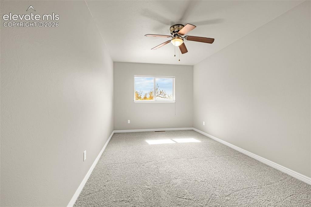 Image 16 of 40: Lower-level bedroom featuring light gray walls, gray carpet, and a white pa