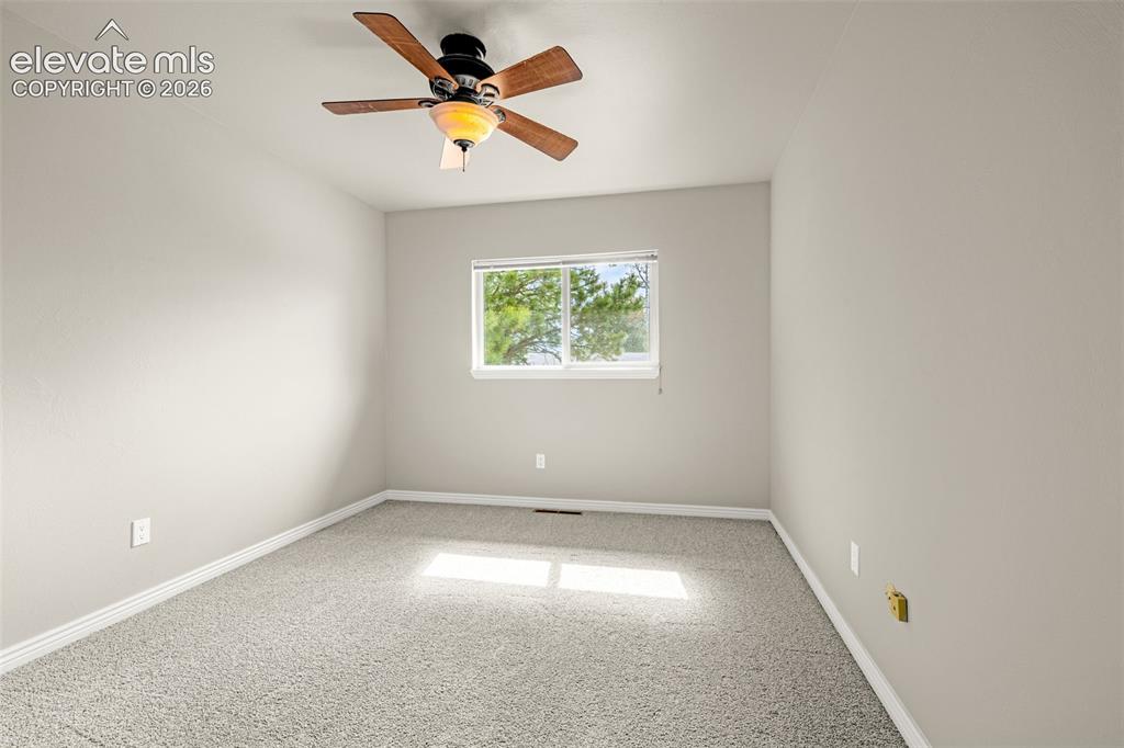 Image 18 of 40: Neutral-toned room featuring a ceiling fan with wood-finish blades, light g