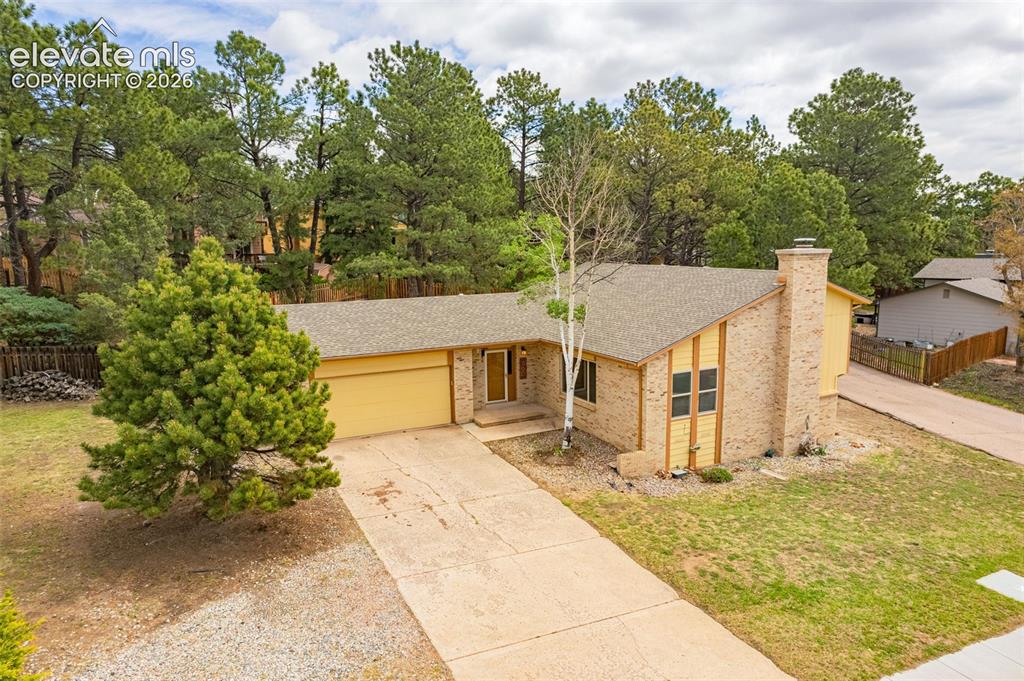 Image 30 of 40: Tri-level residence featuring a two-car garage with a yellow door, brick an