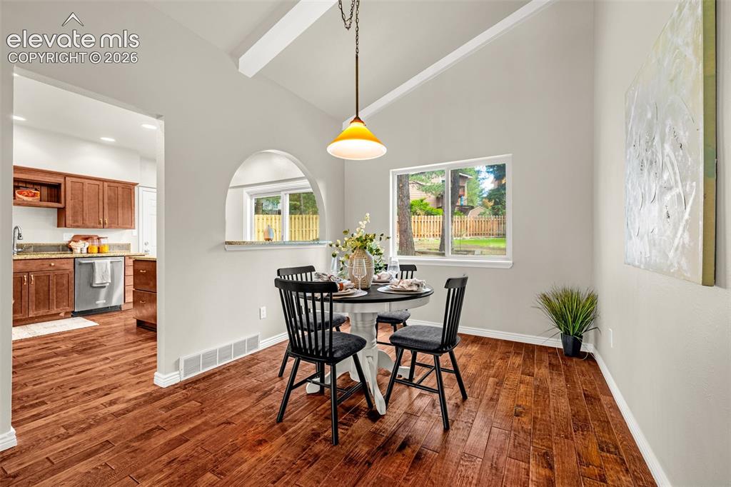 Image 8 of 40: Open-concept living space featuring hardwood flooring, a vaulted ceiling wi