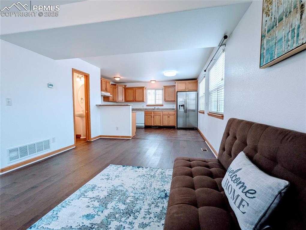 Image 4 of 19: Living area featuring dark wood-style floors and baseboards