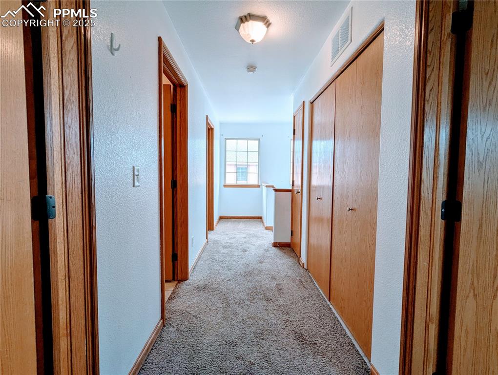 Image 7 of 19: Hallway with light carpet and a textured wall