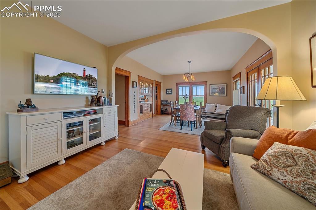 Image 12 of 44: Living room with arched walkways, light wood-style flooring, a chandelier,