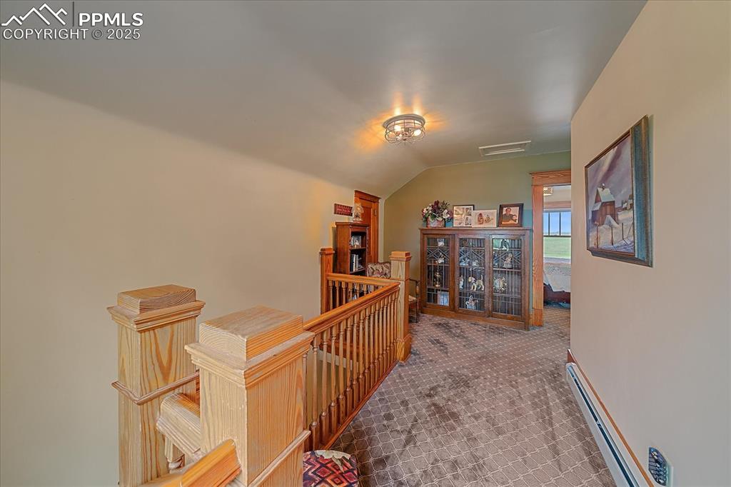 Image 20 of 44: Corridor featuring an upstairs landing, a baseboard radiator, vaulted ceili