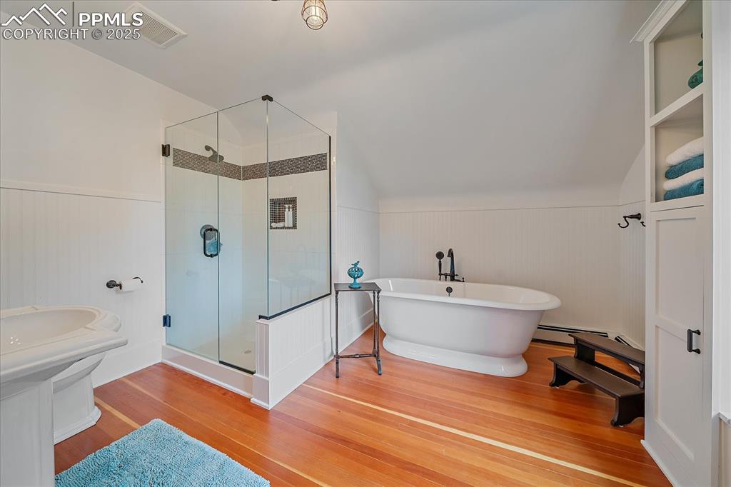 Image 23 of 44: Full bath featuring wood finished floors, a freestanding bath, a stall show