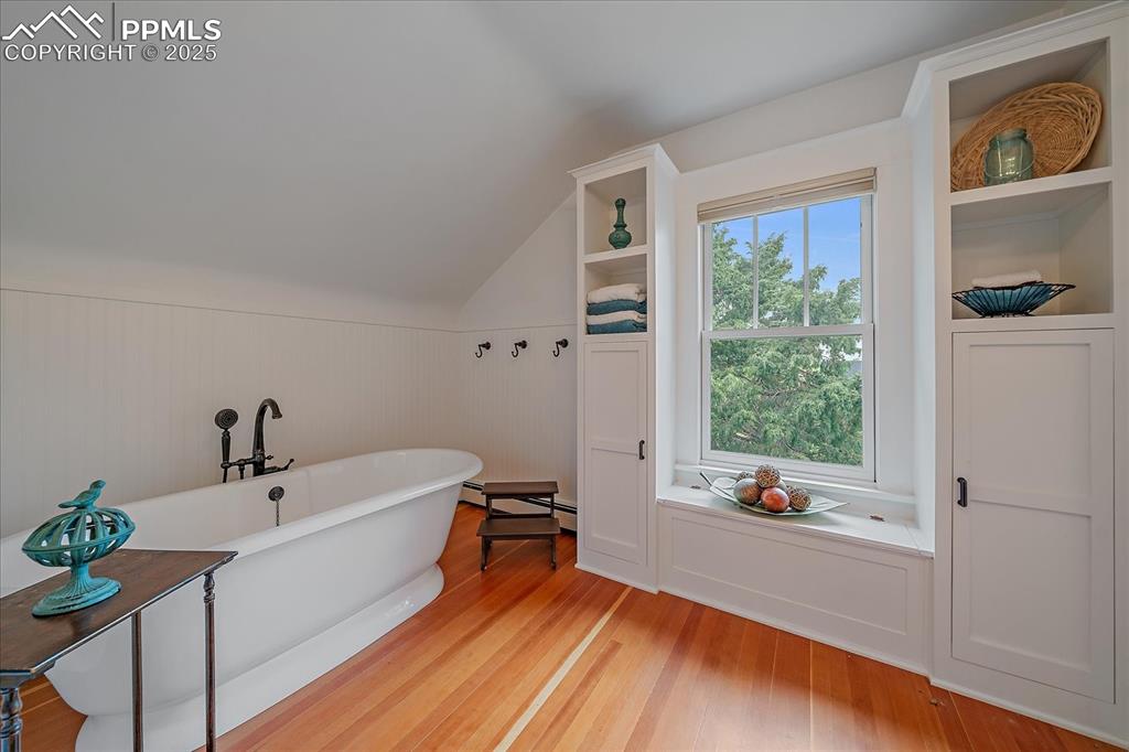 Image 25 of 44: Bathroom featuring a freestanding tub, wood finished floors, lofted ceiling