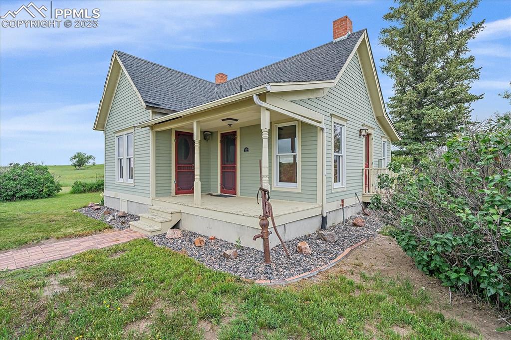 Image 27 of 44: View of front of property with a porch, roof with shingles, a front yard, a