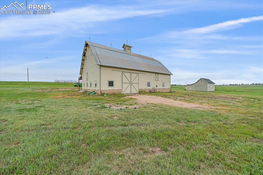 Image 37 of 44: Back of property featuring a barn, an outbuilding, a lawn, and a chimney