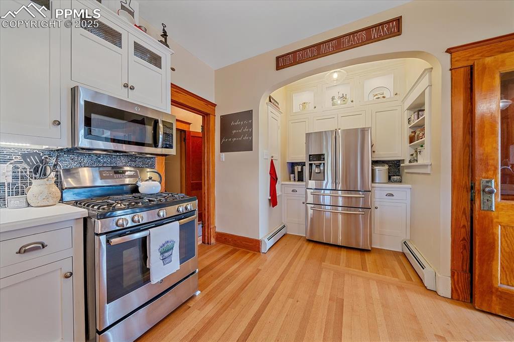 Image 7 of 44: Kitchen with appliances with stainless steel finishes, arched walkways, lig