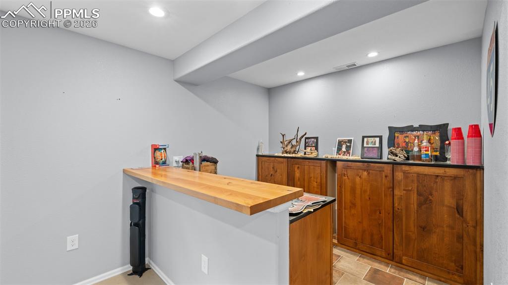 Image 15 of 28: Indoor dry bar featuring butcher block countertops, wood finish cabinets, a