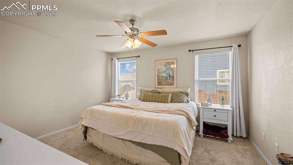 Image 20 of 28: Bedroom with light colored carpet and ceiling fan