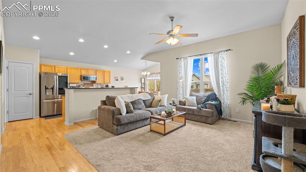 Image 8 of 28: Living room featuring ceiling fan, light wood-style floors, and a chandelie