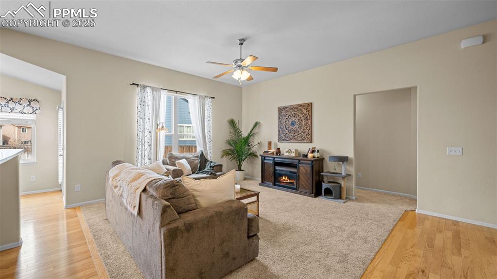 Image 9 of 28: Living area featuring light wood-style floors, a ceiling fan, and a glass c