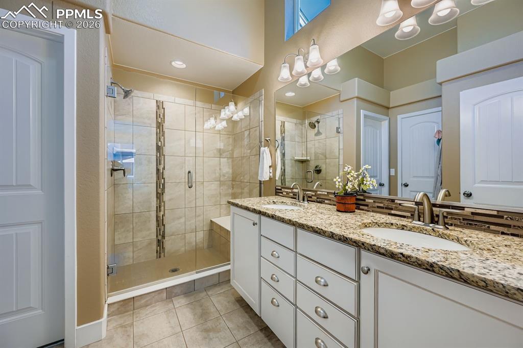 Image 12 of 33: Granite counter w/under mounted sinks, seamless glass shower and tiled floo
