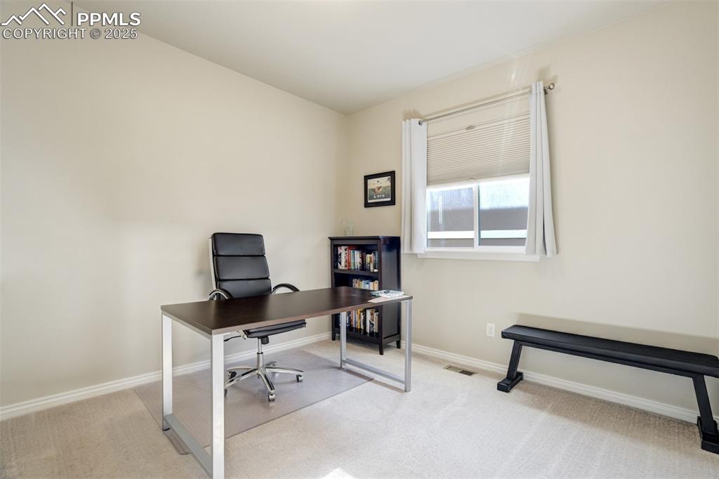 Image 12 of 42: Main level bedroom currently set up as an office