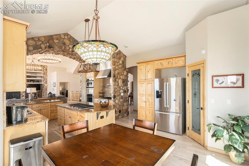 Image 12 of 47: Dining room featuring light wood-type flooring, lofted ceiling, and a chand