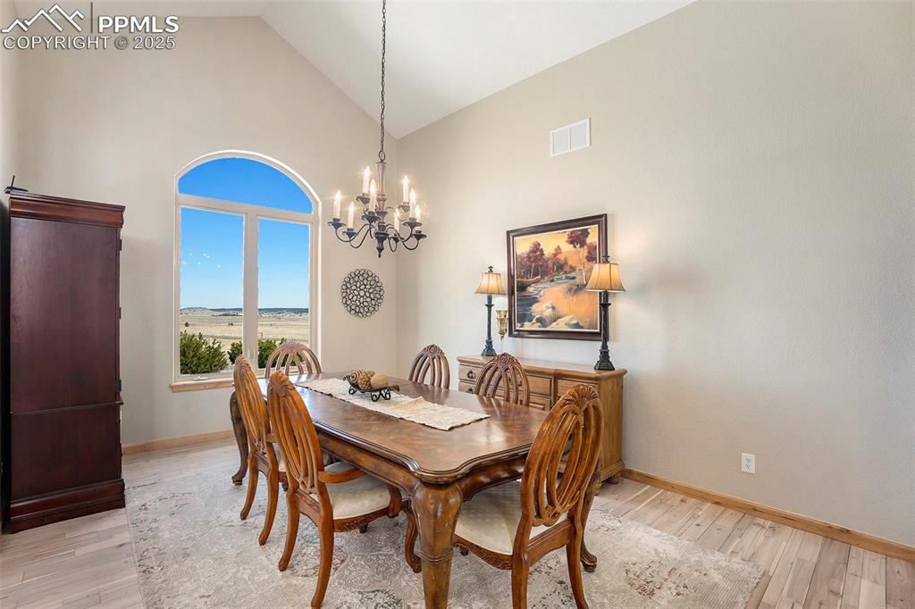 Image 13 of 47: Dining room featuring light wood finished floors, high vaulted ceiling, and