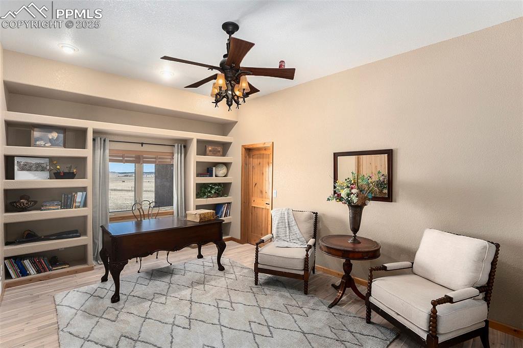 Image 18 of 47: Home office with ceiling fan, light wood-style floors, and built in shelves