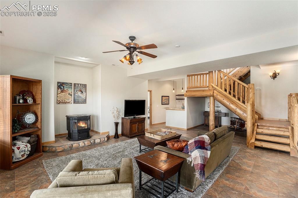 Image 20 of 47: Living area featuring a wood stove, stone tile floors, stairs, and ceiling