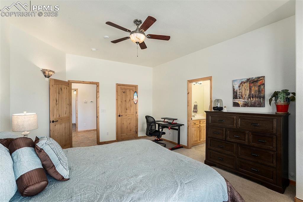 Image 25 of 47: Bedroom featuring light carpet, ceiling fan, and ensuite bathroom